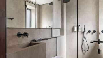 Un bagno moderno con uno specchio grande, un lavabo incassato, un WC e una doccia con comandi multipli.