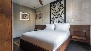 A modern hotel room with a large bed, a ceiling fan, and a decorative wall panel.