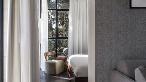 Un dormitorio moderno con un ventanal grande, una cama, un sofá y una pared con motivo de espiga.