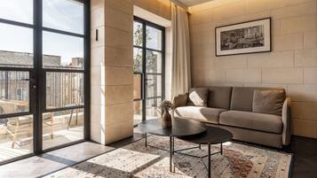 Un salon moderne avec un canapé, une table basse et une grande fenêtre donnant sur la ville.
