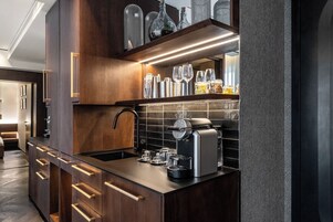 Una cocina moderna con gabinetes de madera oscura, una máquina de espresso integrada y una variedad de vasos.