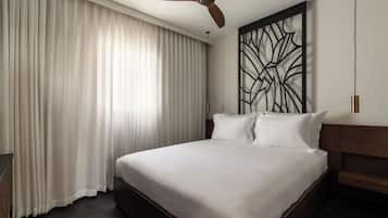 Habitació d'hotel amb un llit gran, un ventilador de sostre i un panell decoratiu a la paret.