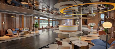 A modern lobby with a reception desk, seating areas, and a high ceiling with unique architectural details.