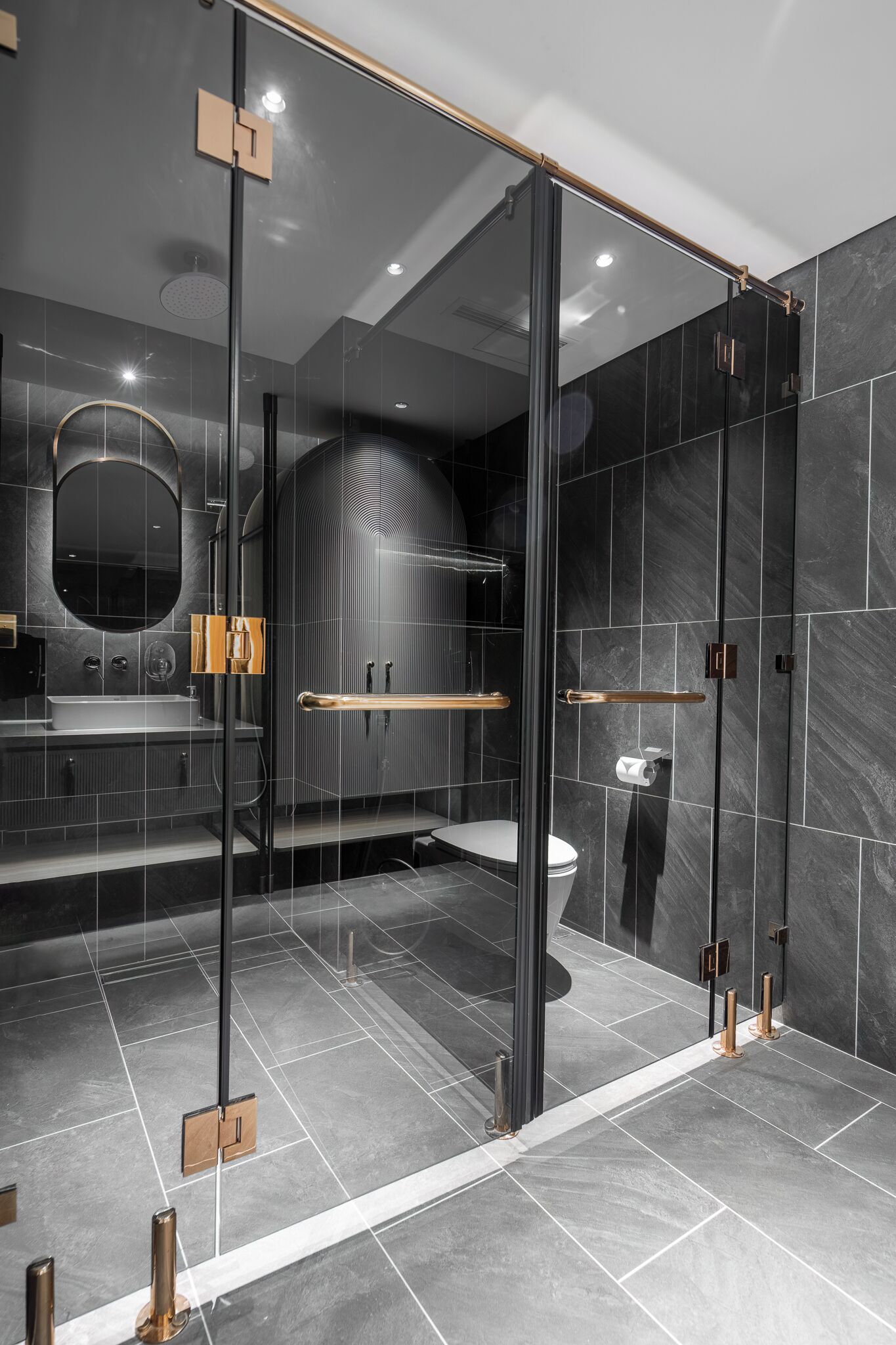 A modern bathroom with a glass-enclosed shower, a round mirror, and a toilet.