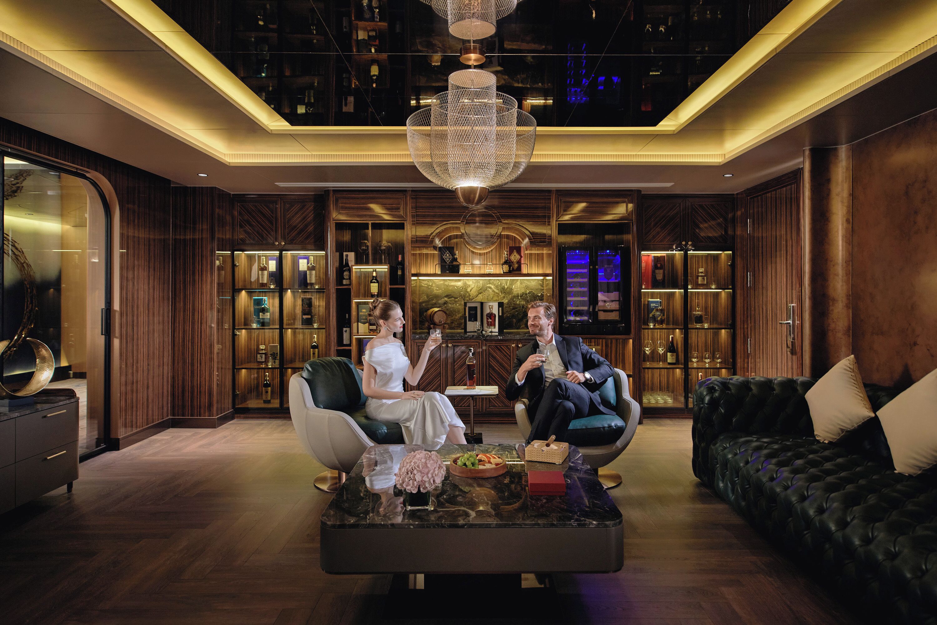 Un hall d’entrée luxueux, agrémenté d’un lustre moderne, de canapés en cuir et d’un bar bien fourni.
