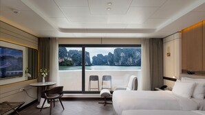 Une chambre d’hôtel avec un grand lit, un bureau avec une chaise, une petite table avec un vase et une télévision.