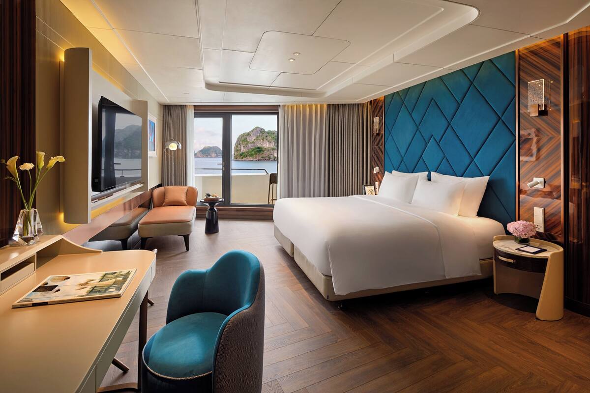 Ein modernes Hotelzimmer mit einem großen Bett, einem Schreibtisch, einem Sessel und Meerblick.