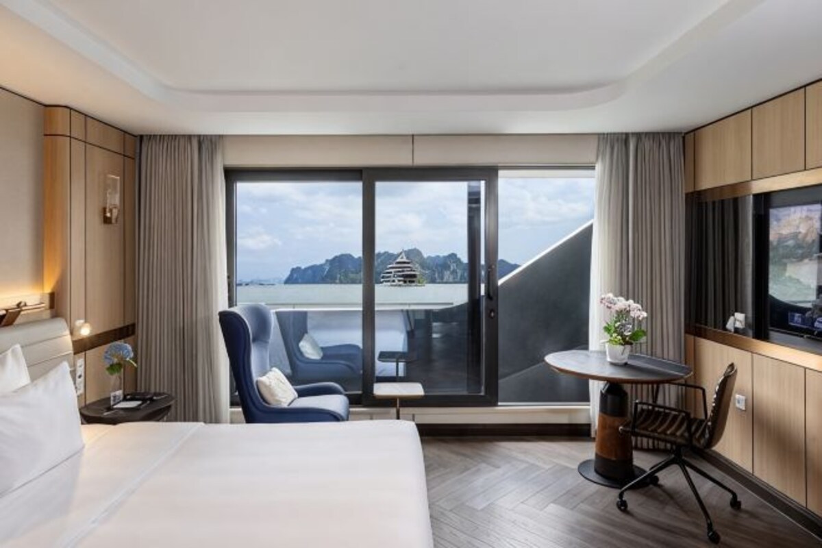 Una habitación de hotel con una cama, un escritorio, una silla, una mesita y un televisor.