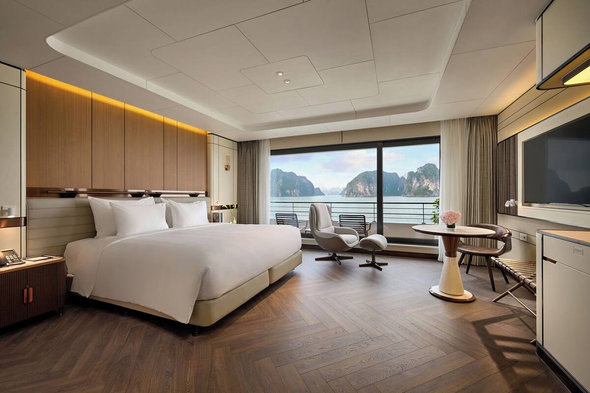 Ein Hotelzimmer mit einem großen Bett, einem Schreibtisch, einem Sessel, einem kleinen Tisch und einem Fernseher.