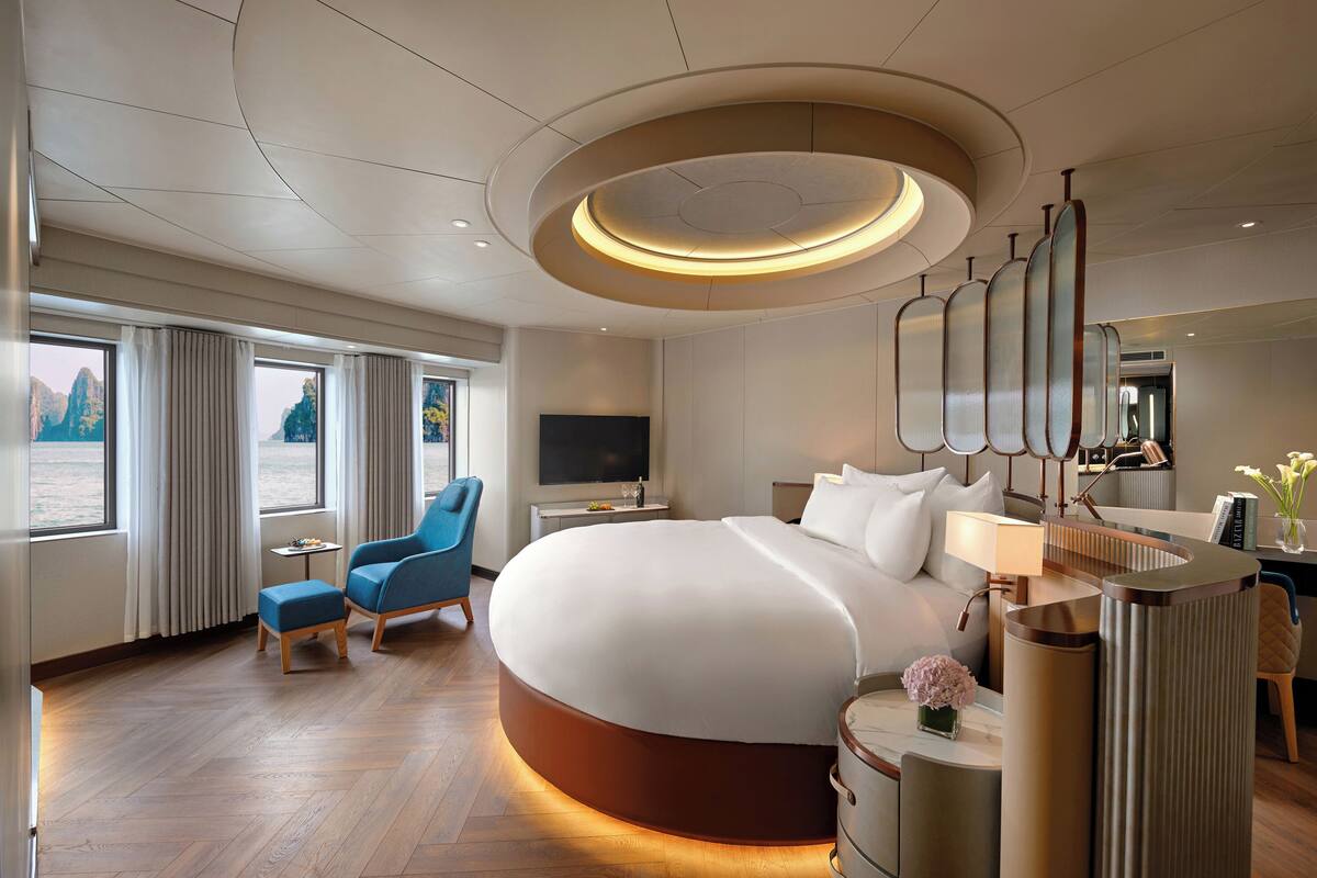 Ein modernes Hotelzimmer mit einem großen Bett, einem Schreibtisch, einem Sessel und einem Fernseher.
