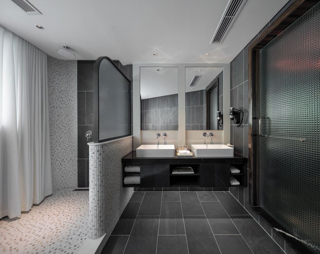 A modern bathroom with two sinks, a large mirror, and a shower area.
