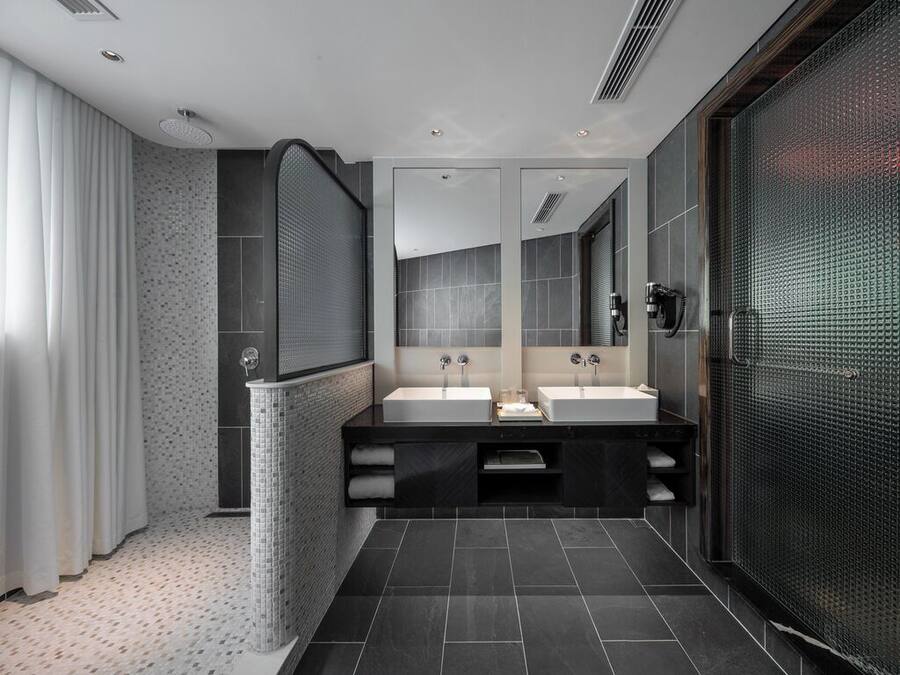 A modern bathroom with two sinks, a large mirror, and a shower area.