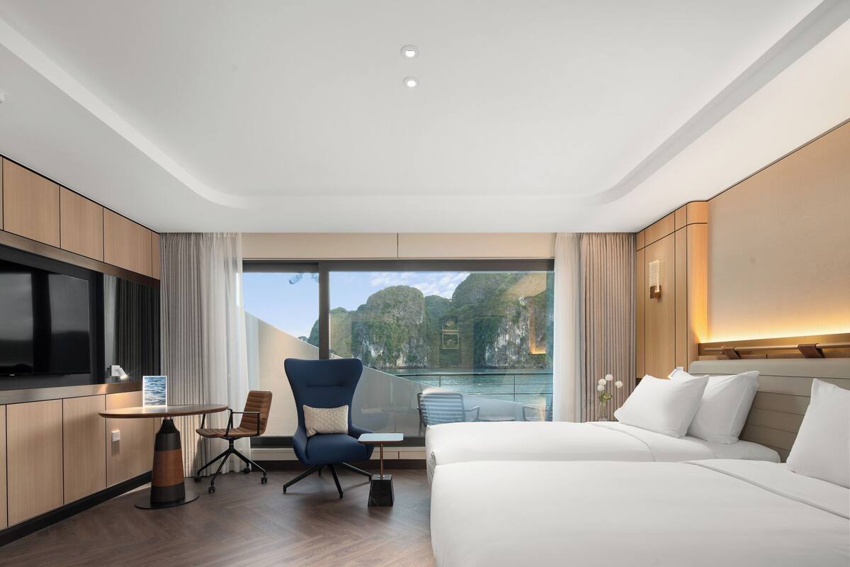 Ein Hotelzimmer mit einem großen Bett, einem Schreibtisch mit Stuhl, einem Fernseher und Meerblick.