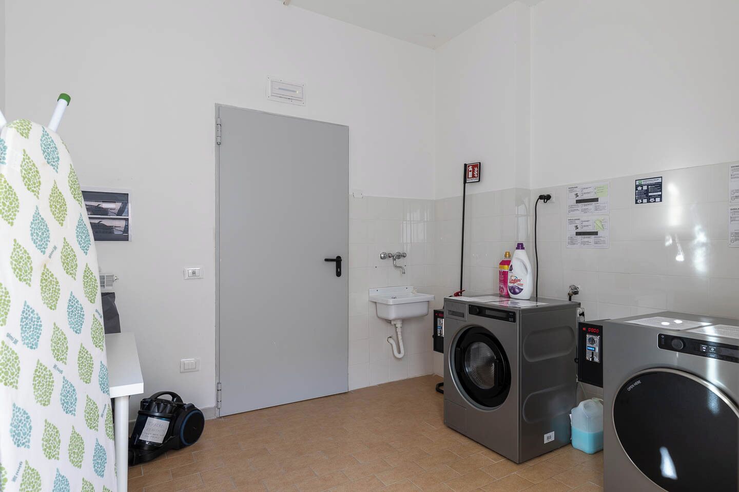 Un lavadero pequeño con lavadora, un lavabo y una cortina de ducha.