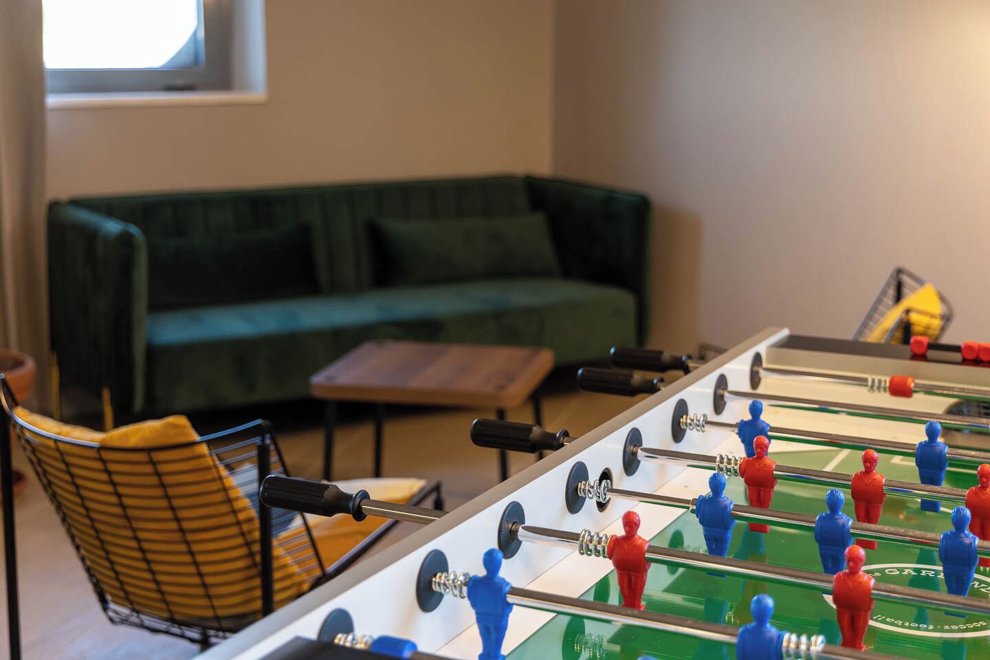 Una mesa de fútbol de mesa en una habitación con un sofá verde y una mesa de centro de madera.
