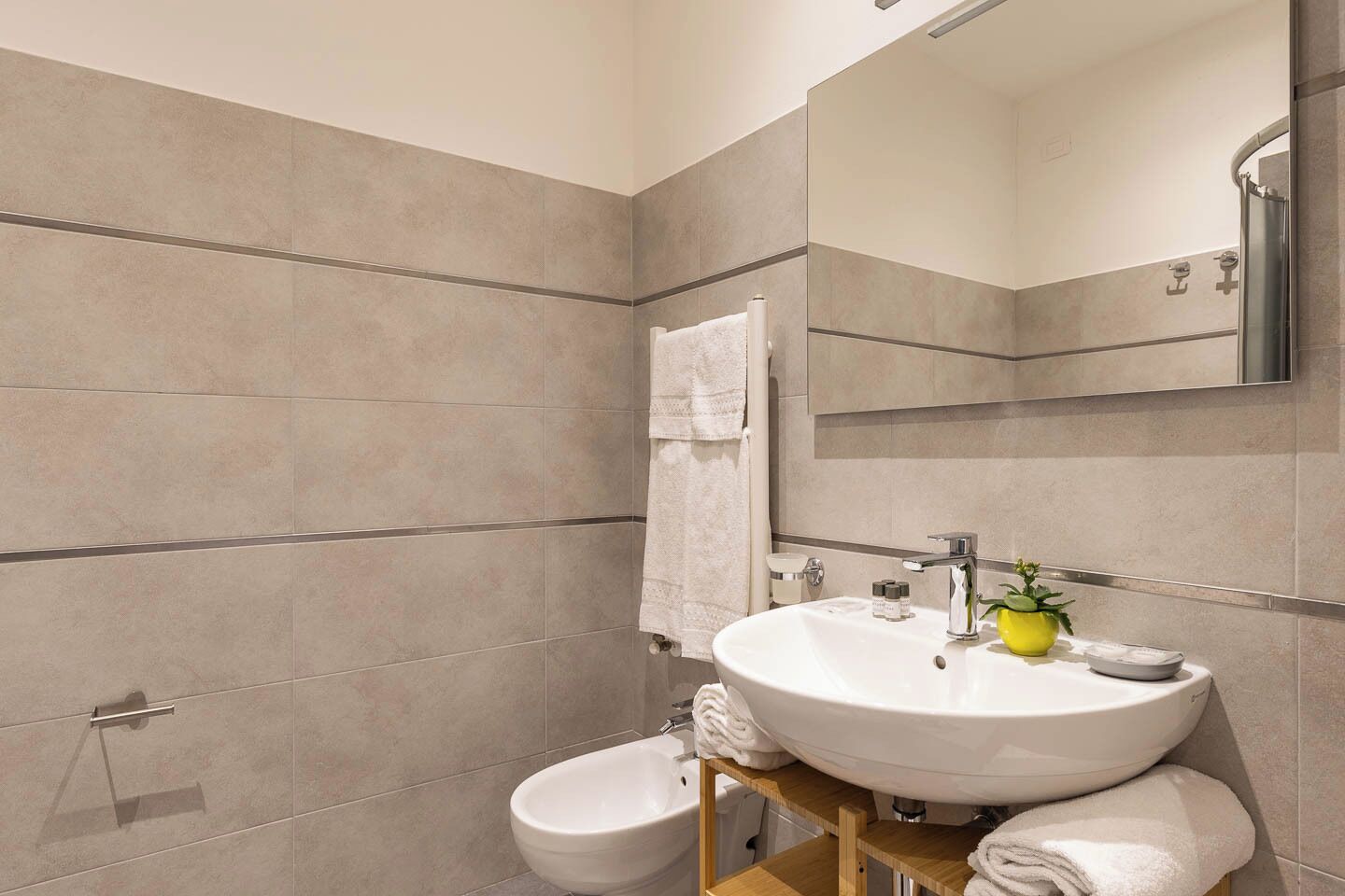 A modern bathroom with a white sink, a mirror, a shower, and a toilet.