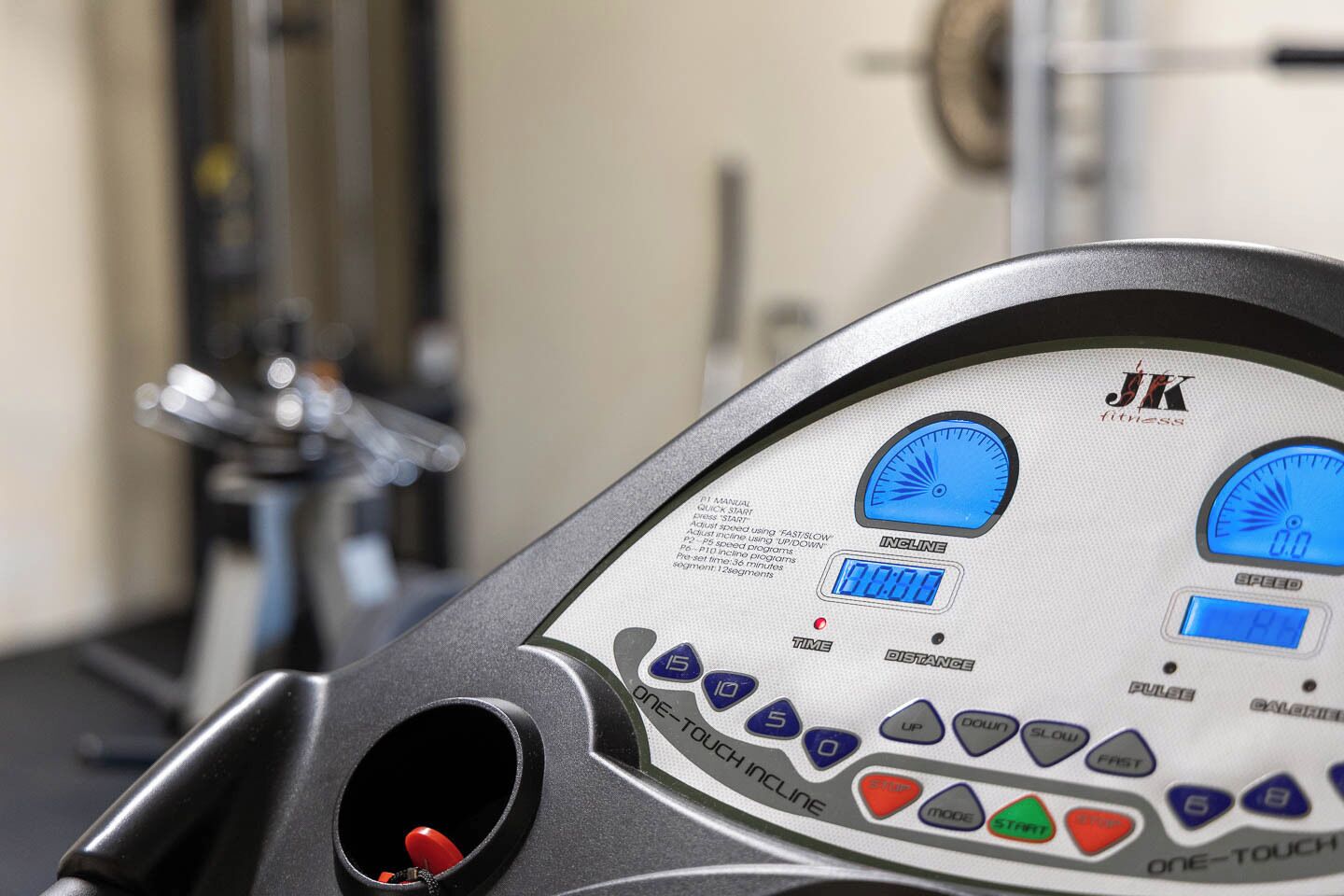 Ein Bedienfeld für Fitnessgeräte mit digitalen Anzeigen für Steigung, Geschwindigkeit und Distanz sowie verschiedenen Tasten zur Einstellung.