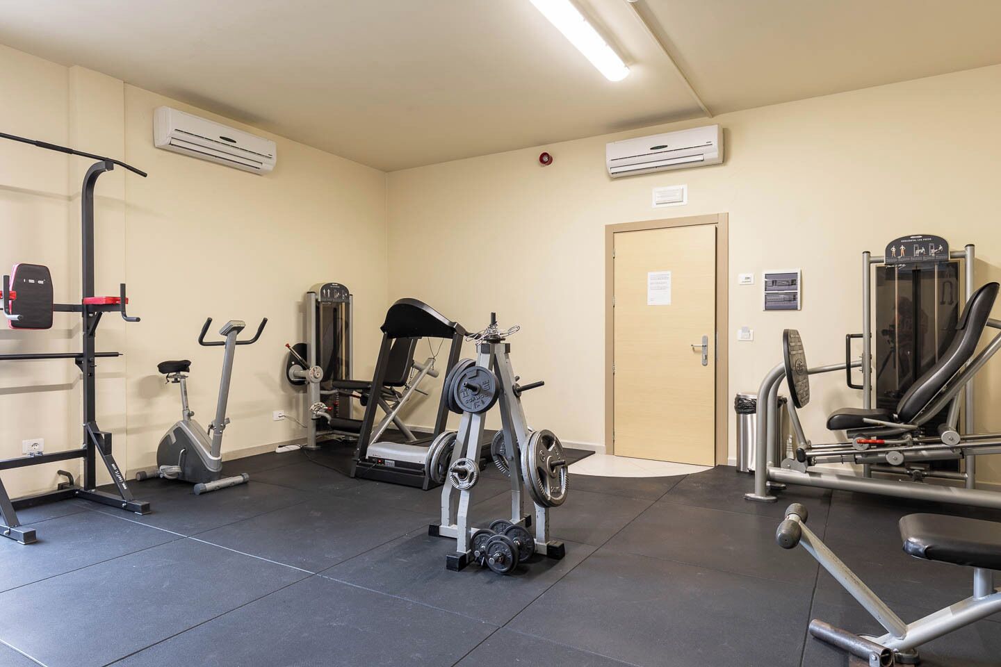Un gimnasio con varios equipos de ejercicio, incluyendo cintas de correr, máquinas de pesas y pesas libres.