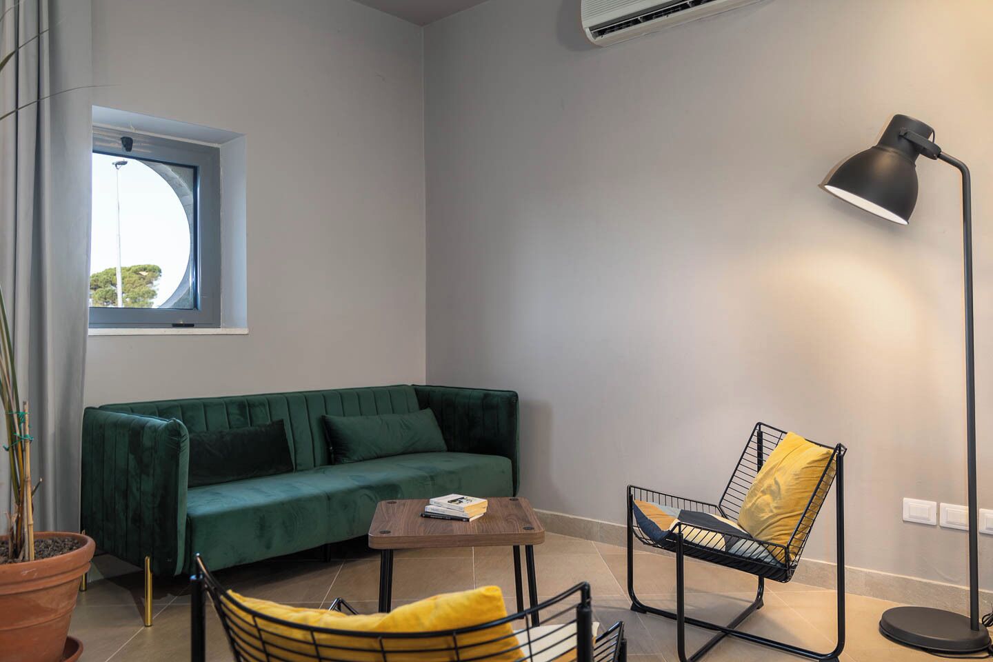 A modern living room with a green sofa, a yellow chair, a small wooden table, and a floor lamp.