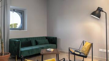 A modern living room with a green sofa, a yellow chair, a small wooden table, and a floor lamp.