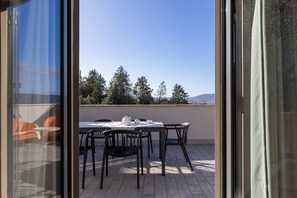 A terrace with a table and chairs, a view of trees and mountains, and a clear sky. - Tuscasì Aparthotel (Sovicille)