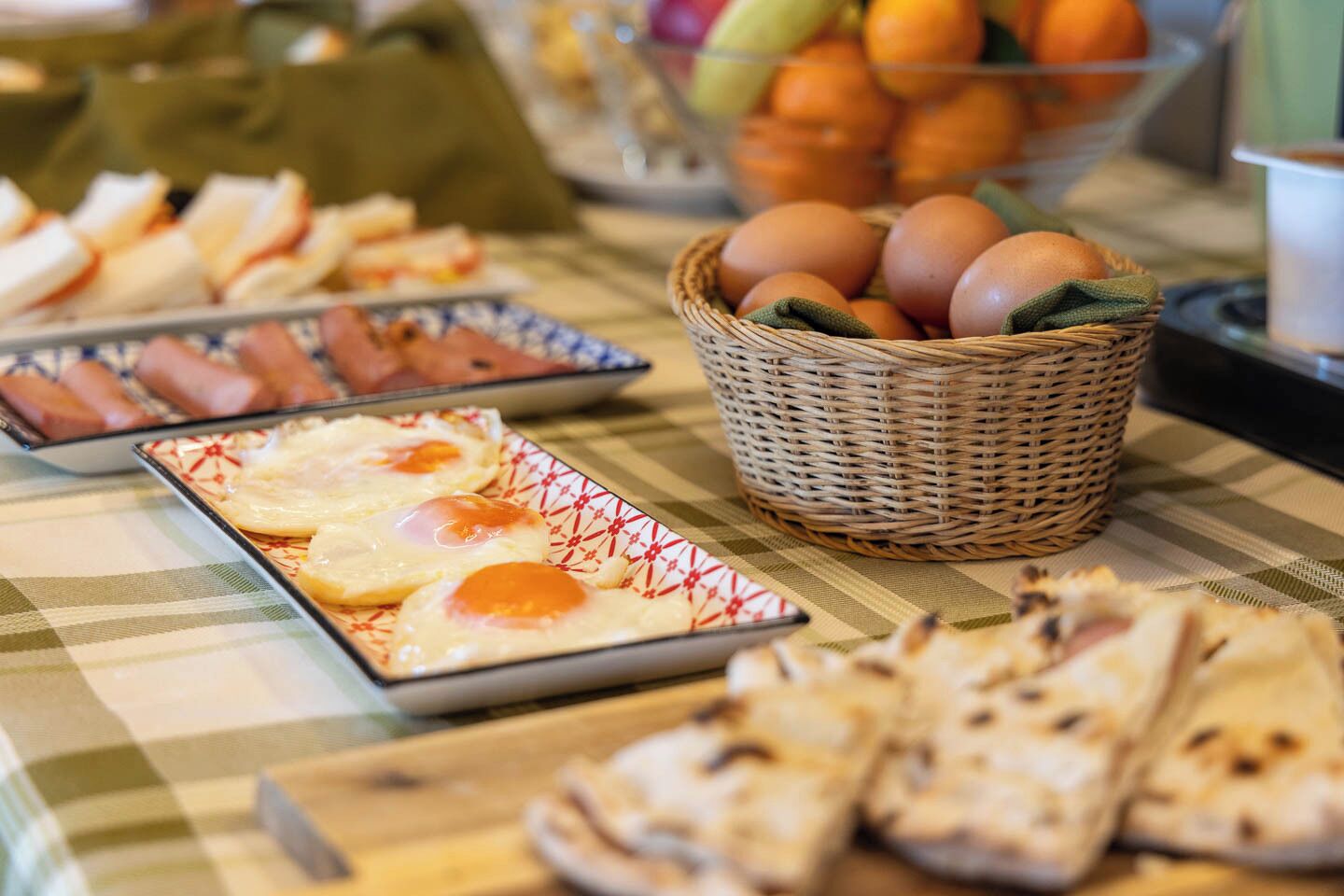 A buffet table with various food items including eggs, bread, and pastries.