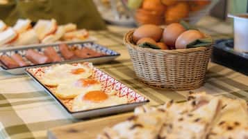 A buffet table with various food items including eggs, bread, and pastries.