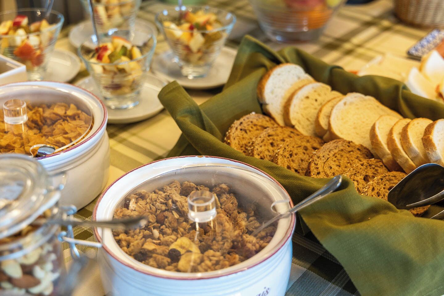 En frukostbuffé med ett varierat utbud av mat, inklusive müsli, bröd och frukt.