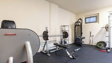 Een sportschool met gewichthefapparatuur, een bank en een power rack.