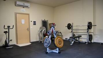 A gym with exercise equipment including a bench press, squat rack, and a stationary bike.