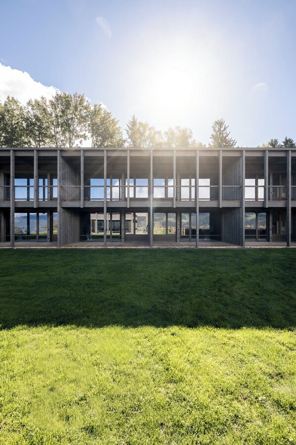 Un edificio moderno con diversi piani e ampie finestre, immerso nel verde.