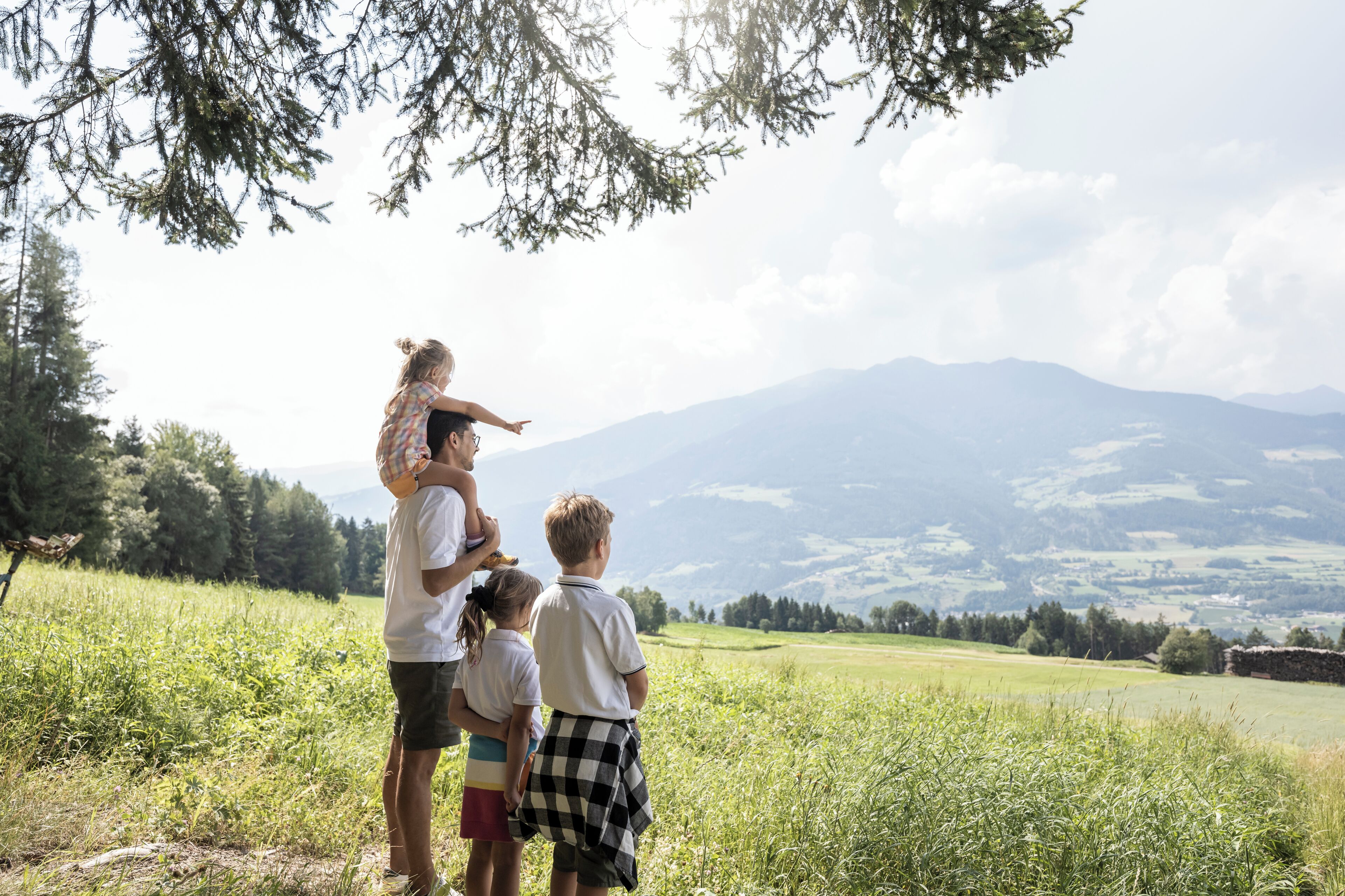 A family standing in a grassy field with a mountain in the background.