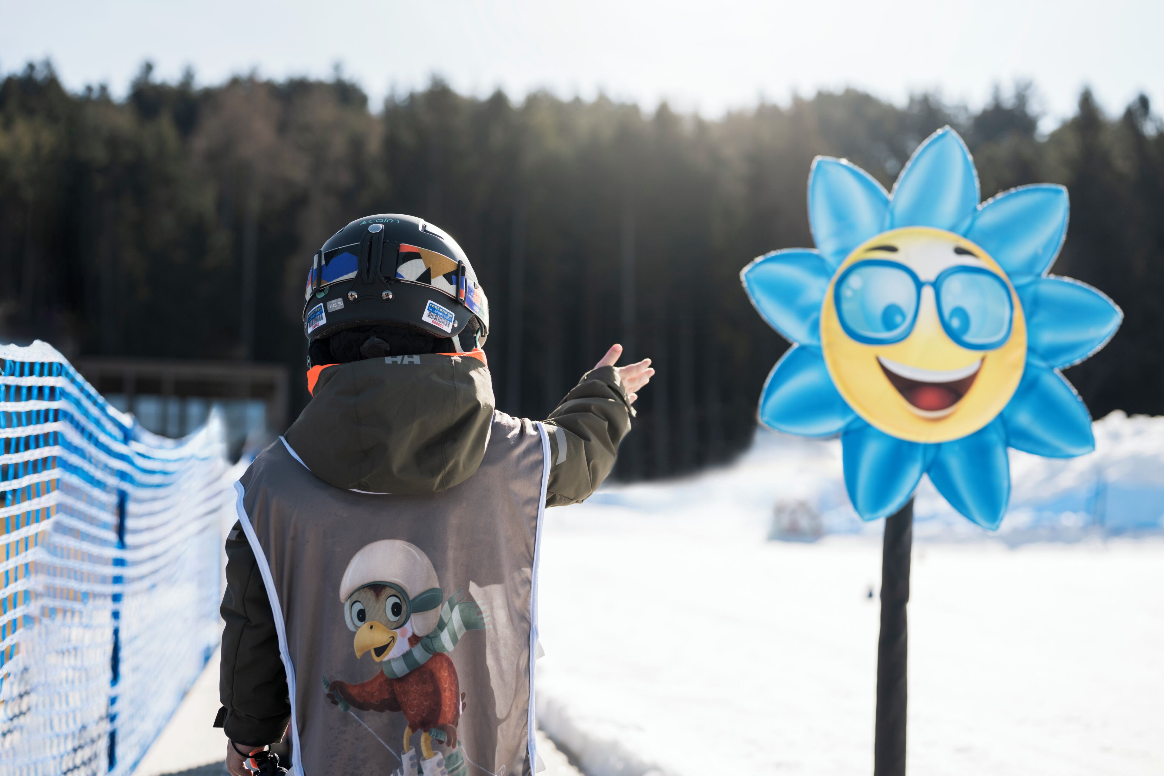 Une personne portant un casque et des équipements de protection, pointant du doigt une silhouette ressemblant à un bonhomme de neige.