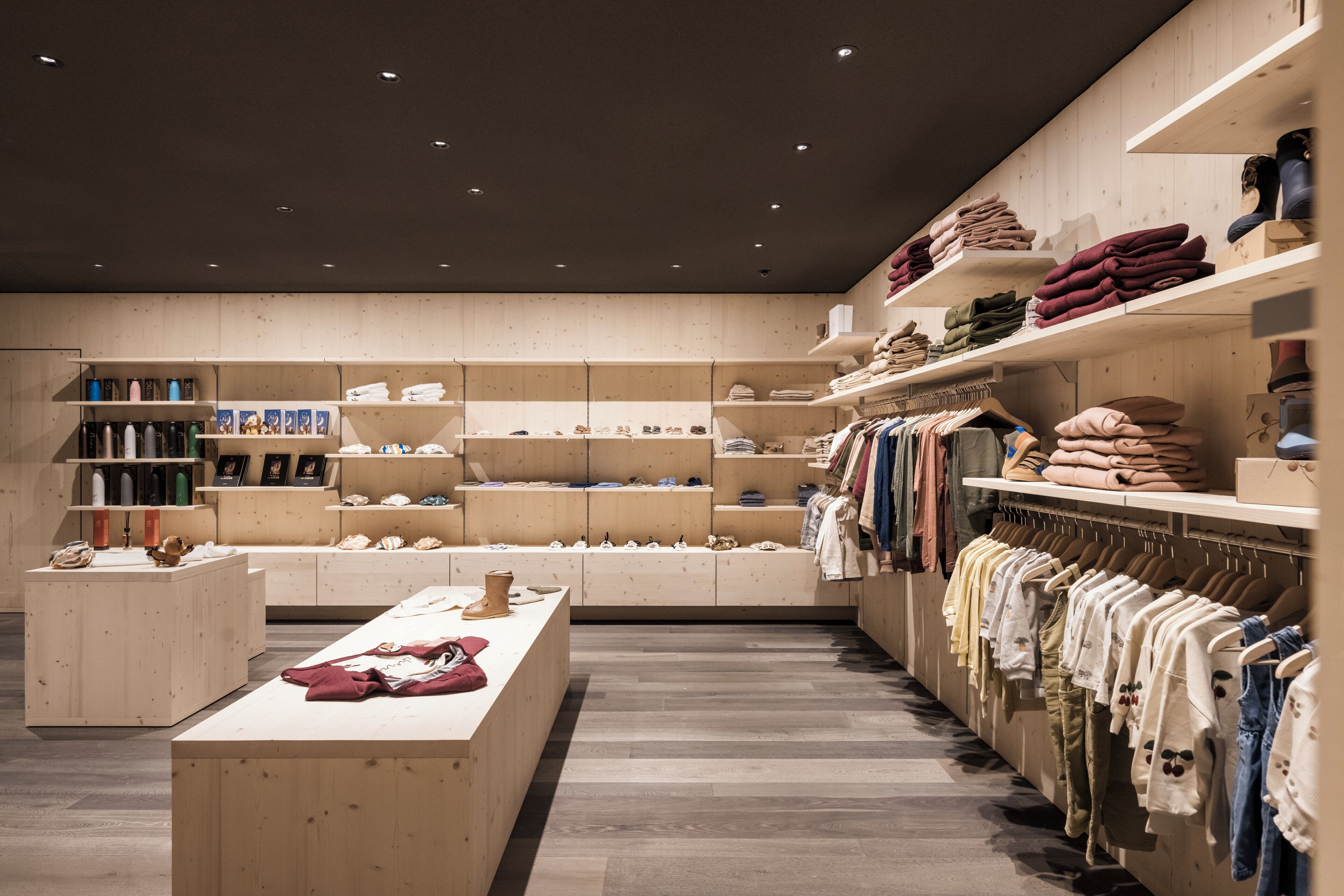 Un negozio moderno con scaffalature in legno che espongono abbigliamento e accessori.