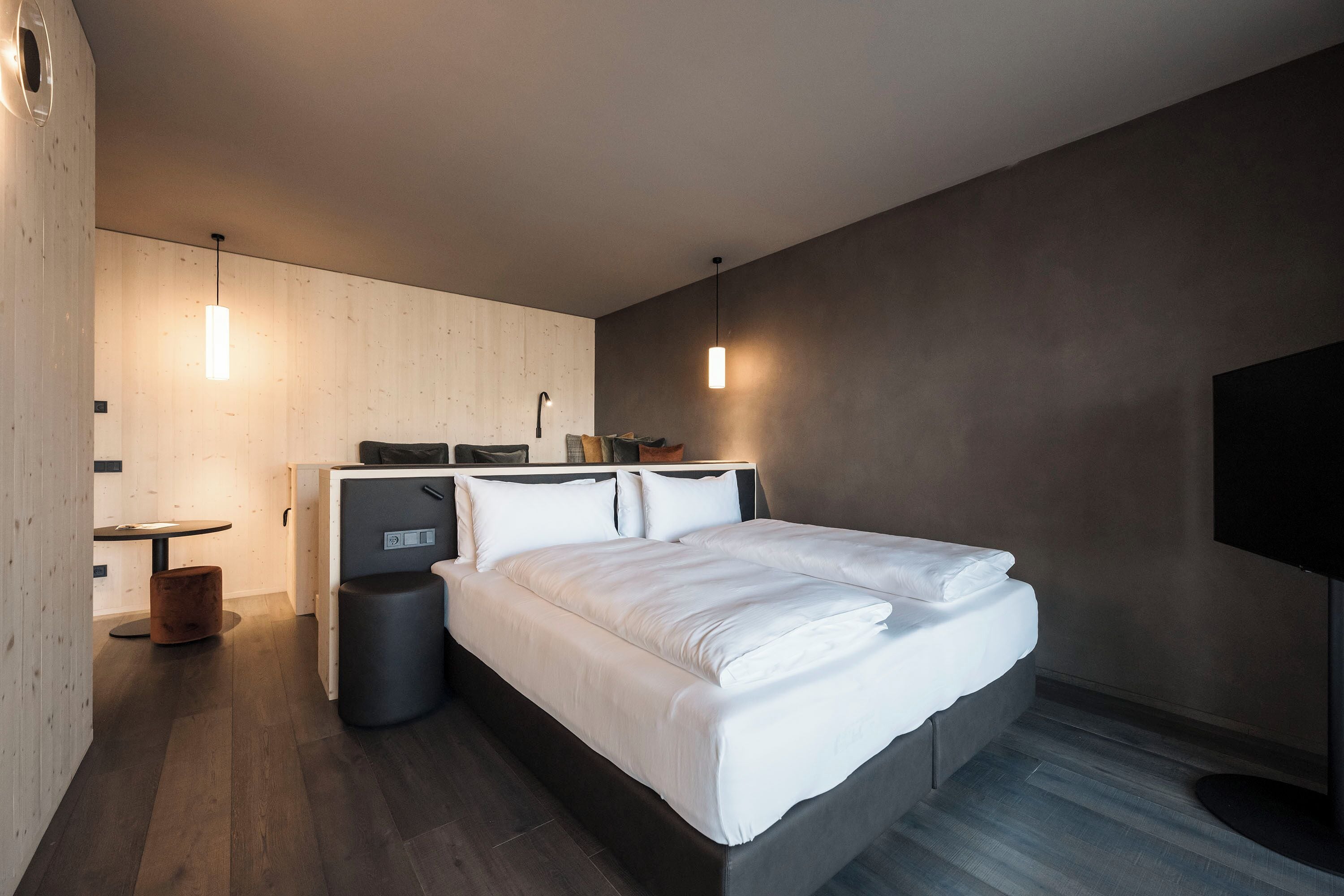 A modern bedroom with a bed, bedside table, and a TV.