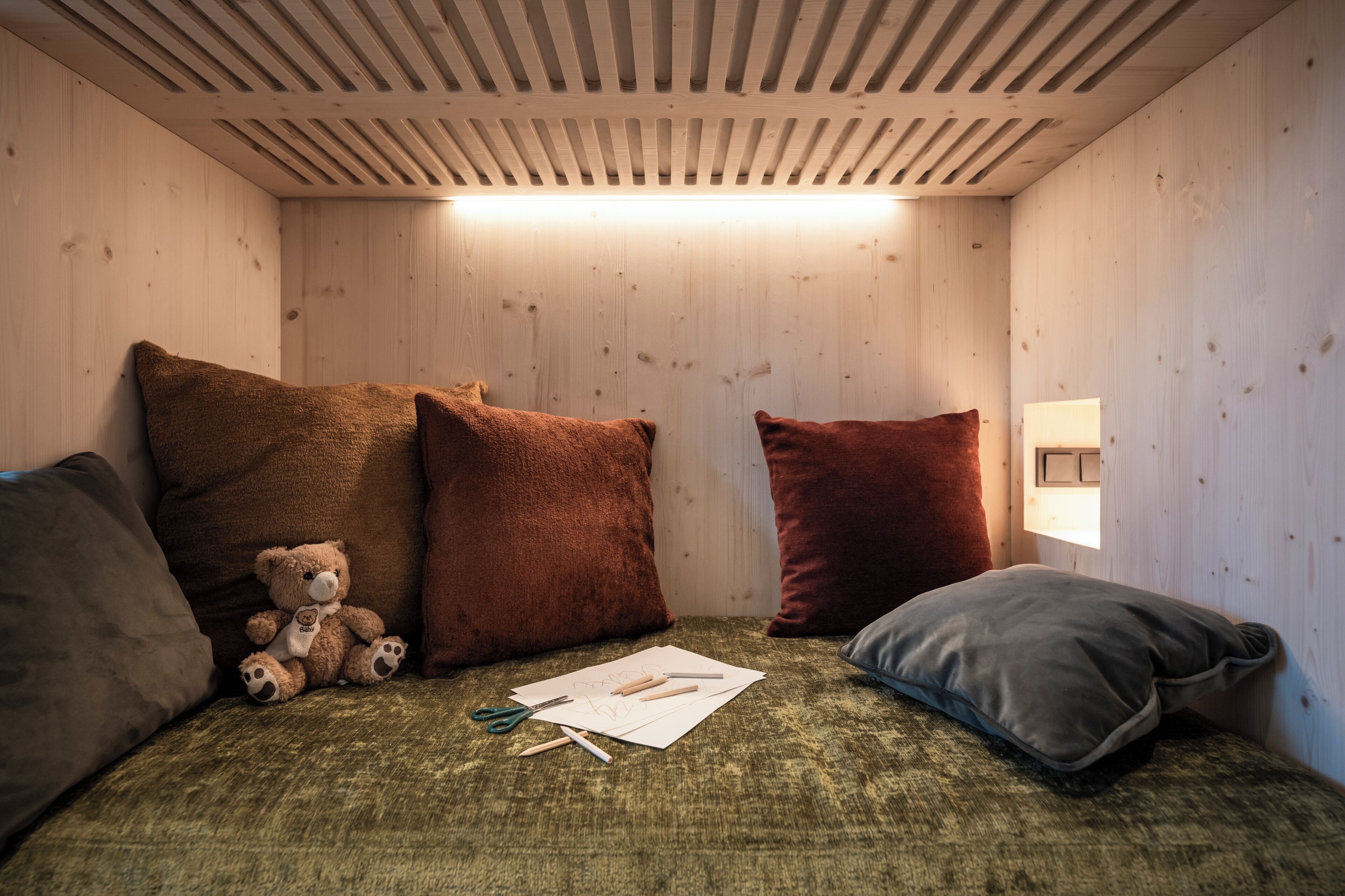 Una habitació acollidora amb un llit, almoines, un os de peluix i una finestra.