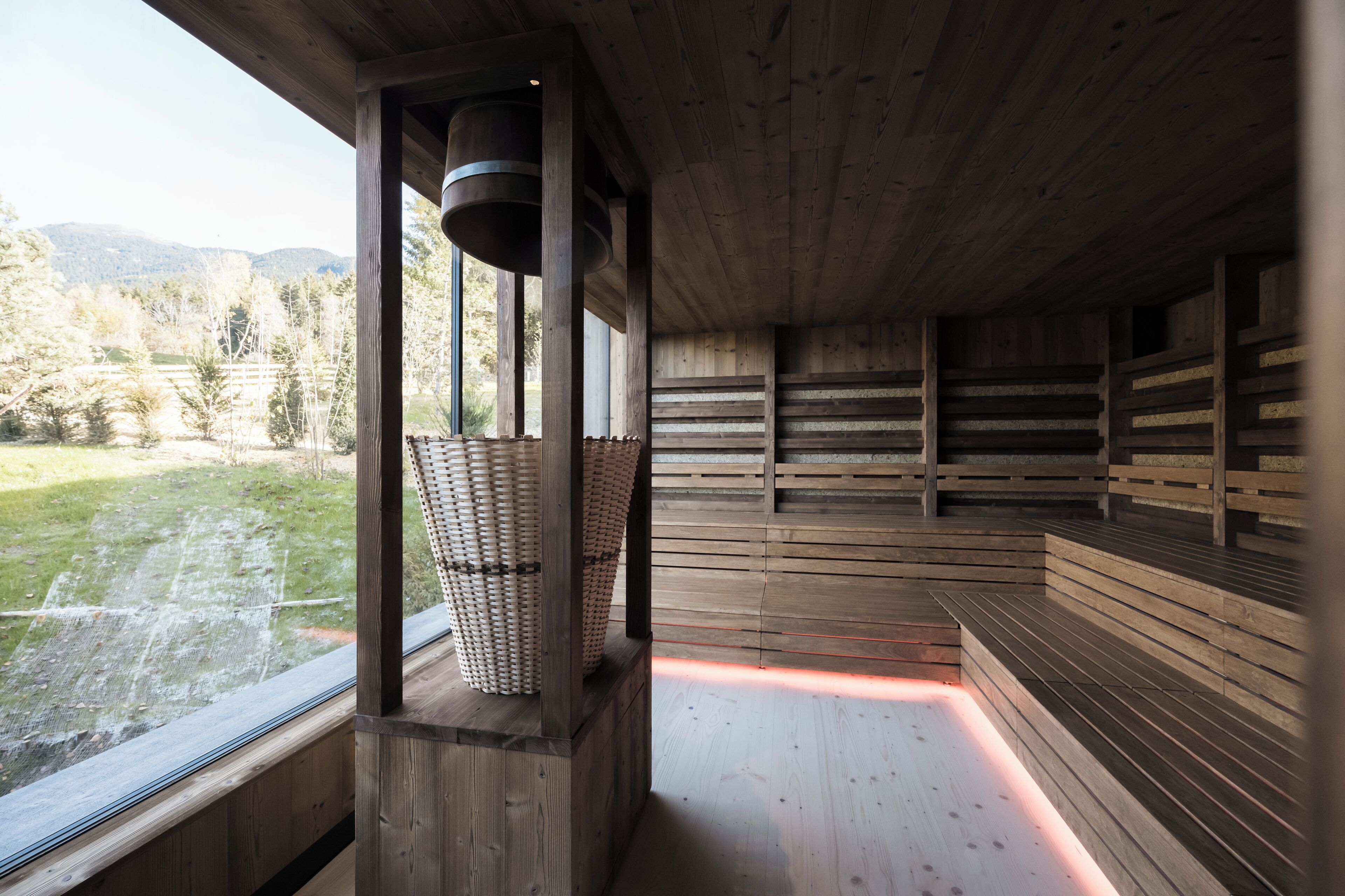 Uma sauna de madeira com bancos e uma janela grande com vista para uma área gramada.