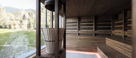 Uma sauna de madeira com bancos e uma janela grande com vista para uma área gramada.