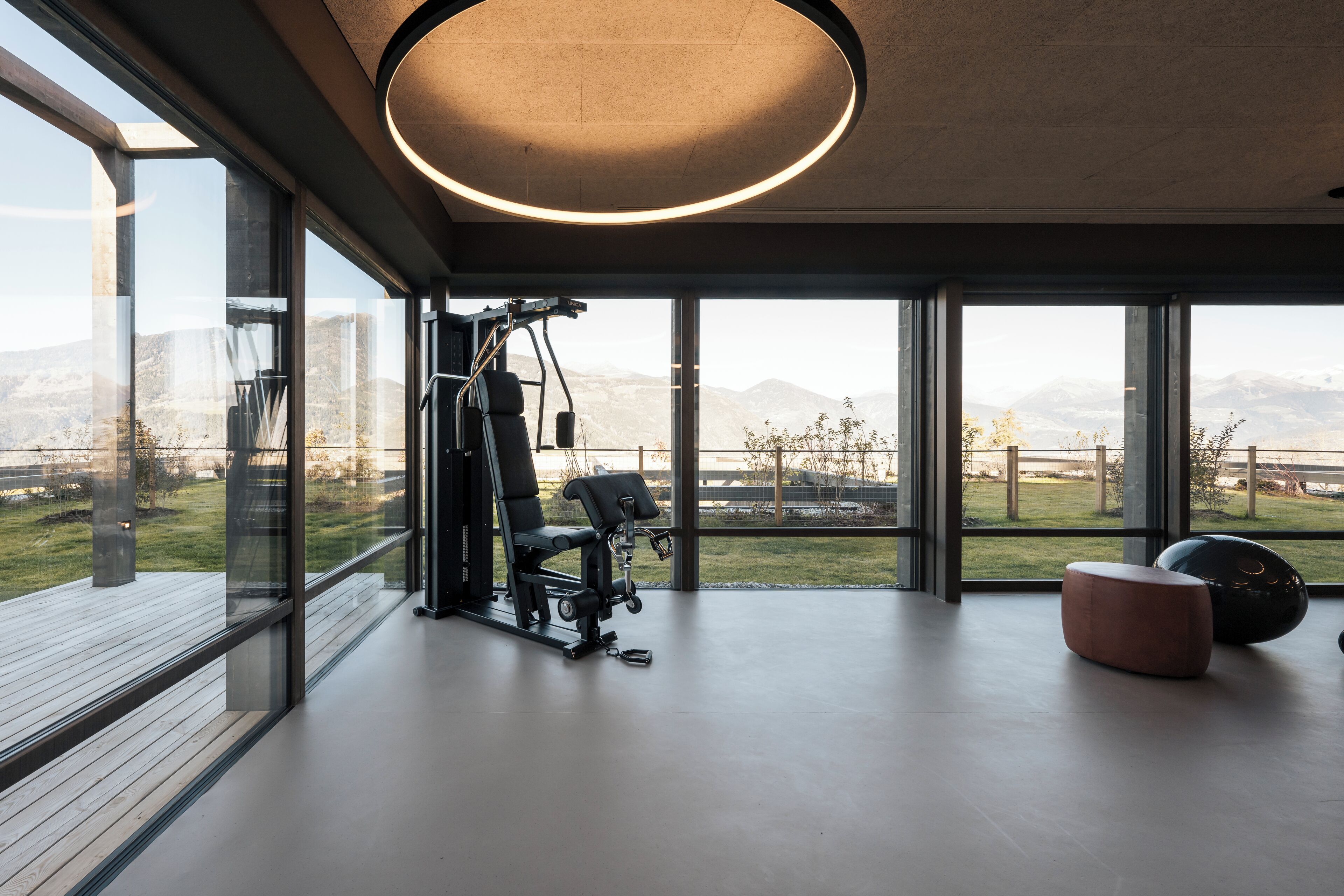 A modern gym with exercise equipment and large windows offering a view of a mountainous landscape.