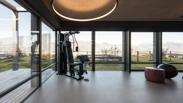 A modern gym with exercise equipment and large windows offering a view of a mountainous landscape.