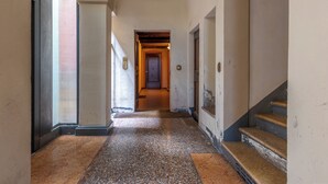 A corridor with a tiled floor, a wooden door at the end, and a staircase on the right. - HouSmart Moline 20 (Bologna)