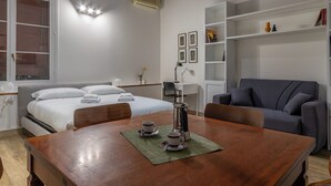 A hotel room with a bed, a desk, a chair, a coffee table, and a bookshelf. - HouSmart Moline 20 (Bologna)