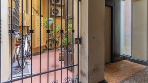 A gated entrance with bicycles parked inside, a potted plant, and a building with a tiled floor. - HouSmart Moline 20 (Bologna)