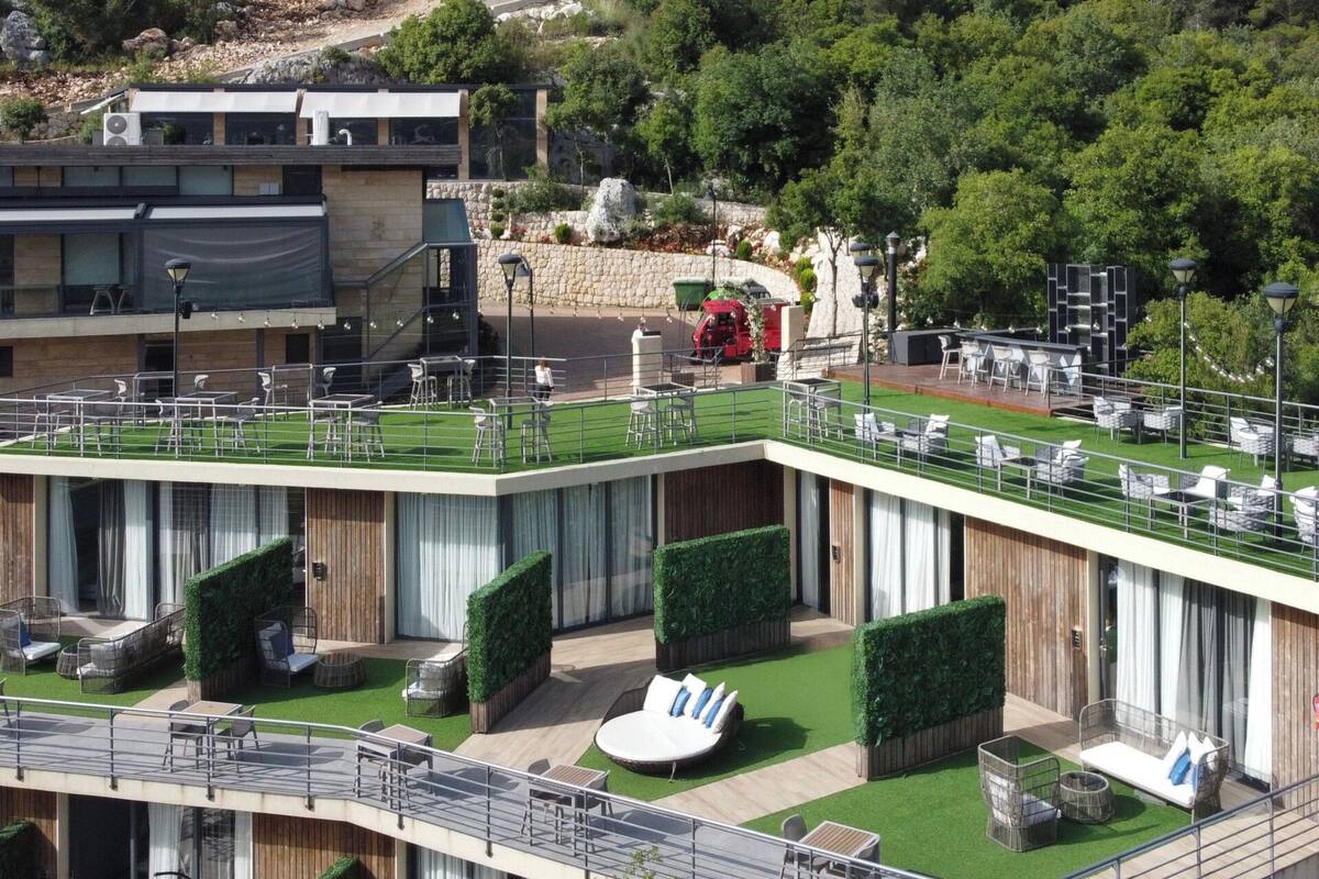 Un edificio moderno con varios niveles, zonas de estar al aire libre y una terraza en la azotea.