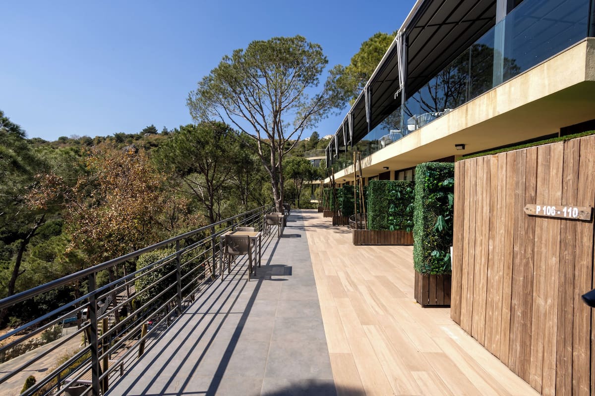 Un edificio moderno con fachada de madera, un balcón con asientos y un cartel que indica los números de las habitaciones.
