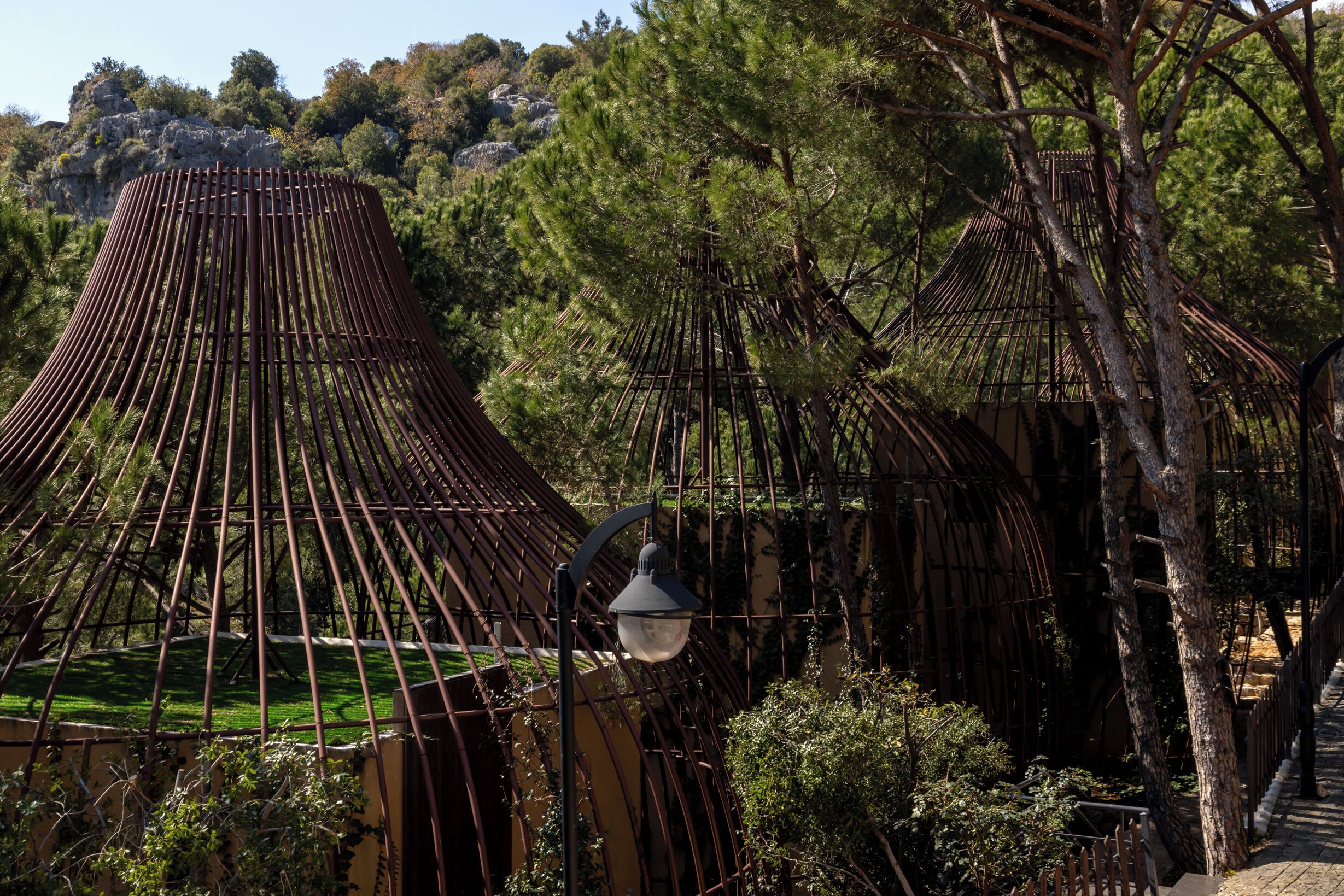 A traditional bamboo structure with a conical roof, surrounded by greenery and trees.