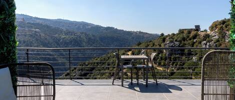 Una terraza con vistas a un paisaje montañoso, una mesa con sillas y un sofá.
