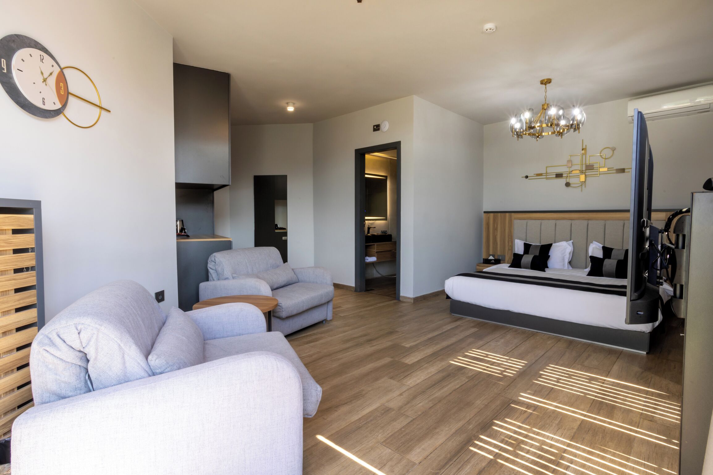 A modern bedroom with a large bed, a sofa, and a small seating area.