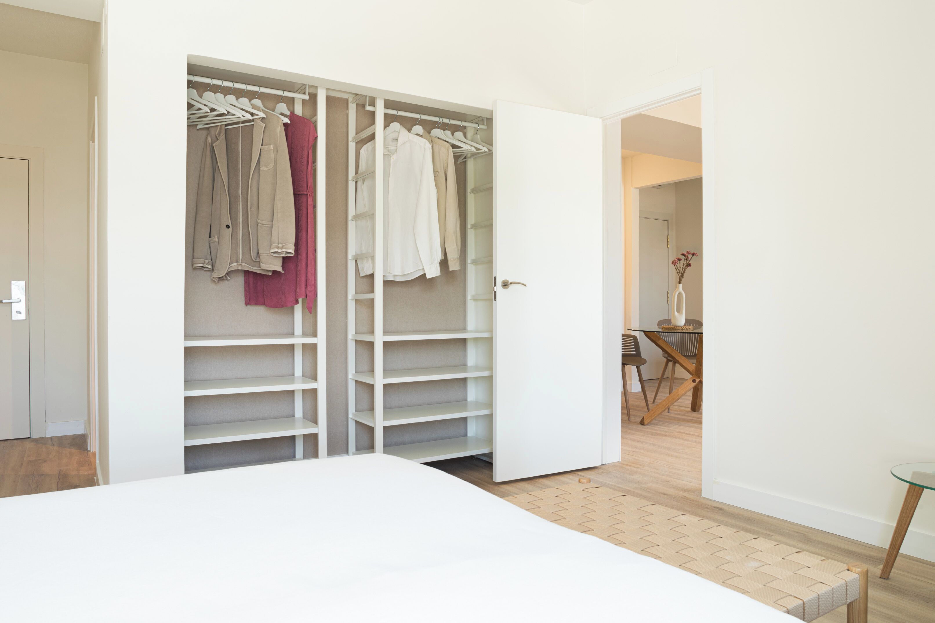 Ein Schlafzimmer mit einem großen Bett, einem begehbaren Kleiderschrank mit Platz zum Aufhängen und einer Essecke mit Tisch und Stühlen.