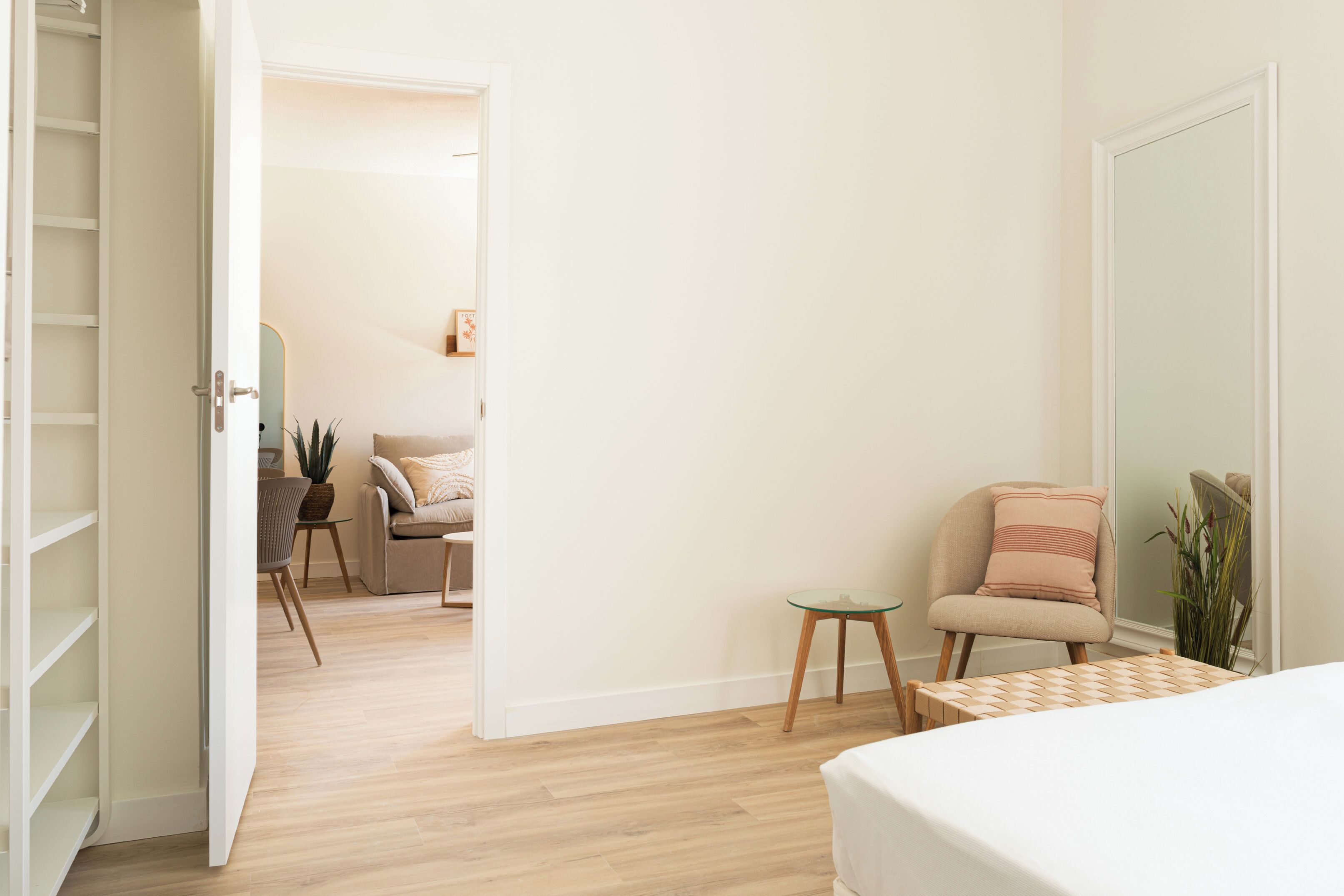 A modern bedroom with a bed, a chair, a small table, and a wardrobe.